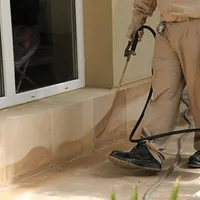 General pest control technician spraying exterior perimeter around a home in Aurora, IL